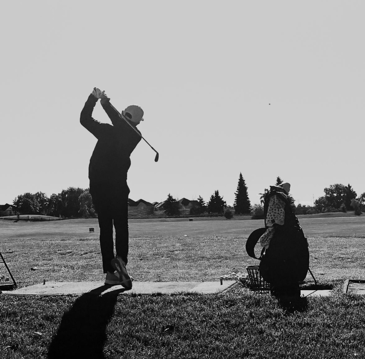 Golfer swinging club in black and white